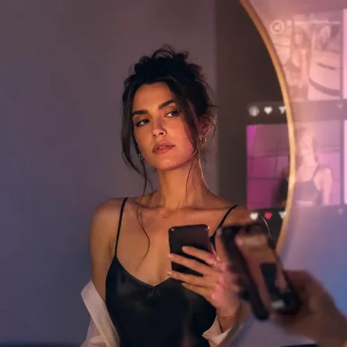 Mujer frente al espejo con móvil reflexionando sobre política del deseo y erotismo digital